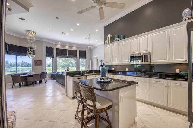 kitchen featuring stainless steel microwave, ceiling fan, a peninsula, crown molding, and light tile patterned floors