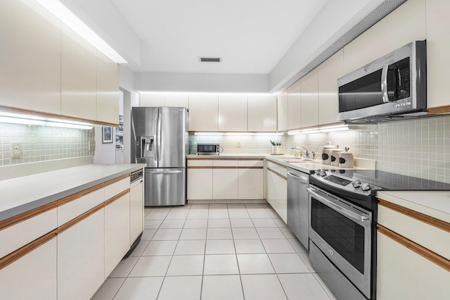 65 Eastgate Dr Unit B, Boynton Beach, FL 33436 - kitchen with appliances with stainless steel finishes, backsplash, light countertops, a sink, and light tile patterned flooring