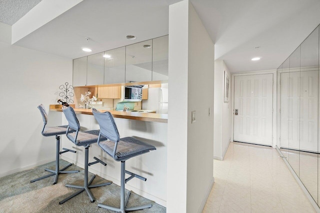 1401 Tidal Pointe Blvd Unit 405, Jupiter, FL 33477 - kitchen featuring stainless steel microwave, freestanding refrigerator, a kitchen bar, baseboards, and recessed lighting