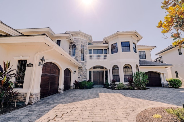 8979 Three Rail Dr, Boynton Beach, FL 33472 - view of front of house featuring a balcony, decorative driveway, french doors, stone siding, and stucco siding