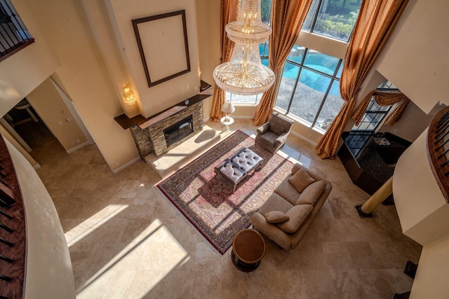 8979 Three Rail Dr, Boynton Beach, FL 33472 - living area featuring a stone fireplace, a high ceiling, a chandelier, and baseboards