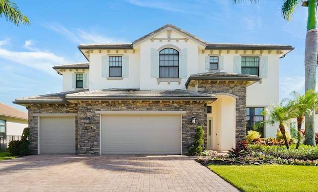 9196 Grand Prix Ln, Boynton Beach, FL 33472 - mediterranean / spanish-style home with an attached garage, stucco siding, stone siding, decorative driveway, and a tile roof