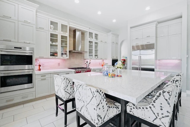 9196 Grand Prix Ln, Boynton Beach, FL 33472 - kitchen featuring appliances with stainless steel finishes, wall chimney exhaust hood, a kitchen bar, a large island, and decorative backsplash
