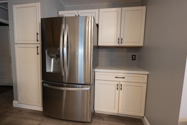 1325 Strawberry Ln, West Palm Beach, FL 33415 - kitchen with stainless steel fridge, light countertops, decorative backsplash, wood finished floors, and white cabinets