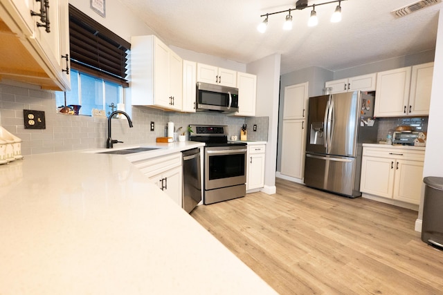 1325 Strawberry Ln, West Palm Beach, FL 33415 - kitchen featuring stainless steel appliances, a sink, decorative backsplash, light countertops, and white cabinets