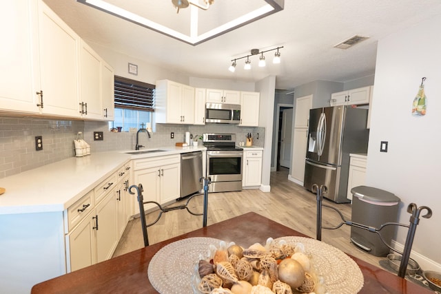 1325 Strawberry Ln, West Palm Beach, FL 33415 - kitchen featuring stainless steel appliances, a sink, light wood finished floors, backsplash, and white cabinets