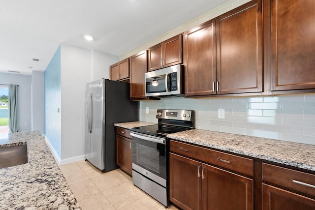 852 Gairloch Ln, Fort Pierce, FL 34947 - kitchen with stainless steel appliances, tasteful backsplash, light tile patterned floors, light stone countertops, and baseboards