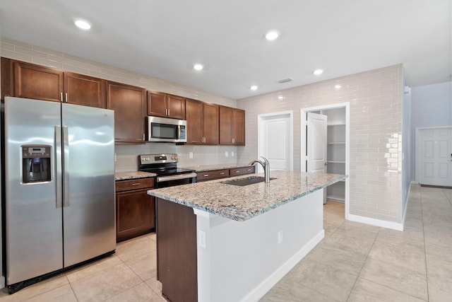 852 Gairloch Ln, Fort Pierce, FL 34947 - kitchen with appliances with stainless steel finishes, a sink, light tile patterned floors, light stone counters, and an island with sink