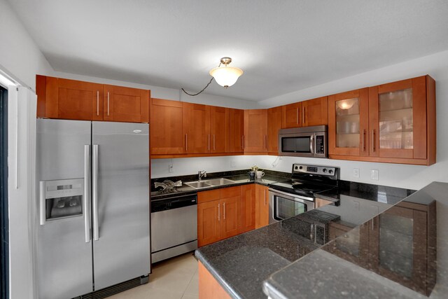 2938 SW 12th St, Deerfield Beach, FL 33442 - kitchen with appliances with stainless steel finishes, dark stone counters, glass insert cabinets, a sink, and brown cabinetry