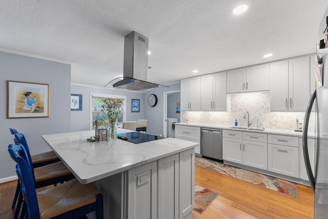 454 Tequesta Dr, Tequesta, FL 33469 - kitchen with stainless steel appliances, island range hood, a sink, light wood finished floors, and a center island
