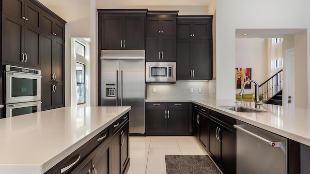 8520 Lewis River Rd, Delray Beach, FL 33446 - kitchen featuring built in appliances, a sink, light countertops, light tile patterned floors, and tasteful backsplash