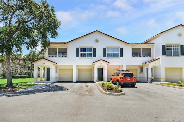 174 SE Kitching Cir Unit 174, Stuart, FL 34994 - view of front facade featuring a garage, driveway, stucco siding, a balcony, and a tiled roof