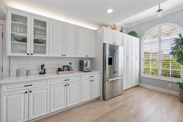 kitchen featuring stainless steel fridge with ice dispenser, baseboards, backsplash, white cabinetry, and ornamental molding