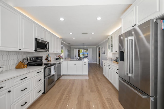 kitchen featuring stainless steel appliances, a peninsula, white cabinetry, recessed lighting, and a sink