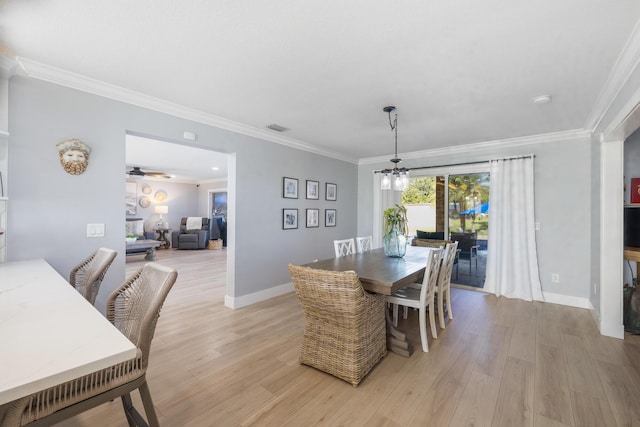 dining space with light wood-style flooring, a chandelier, ornamental molding, and baseboards