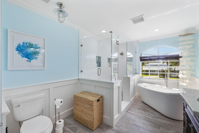 bathroom with a stall shower, wood finished floors, a soaking tub, a wainscoted wall, and toilet
