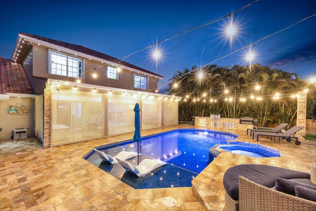 pool at twilight featuring a patio area and a pool with connected hot tub