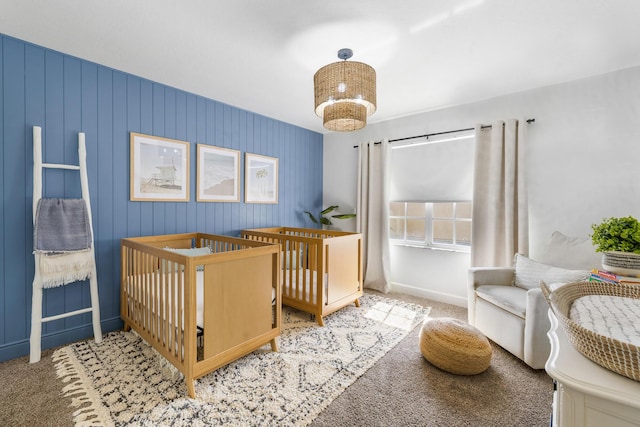 carpeted bedroom with a crib and baseboards