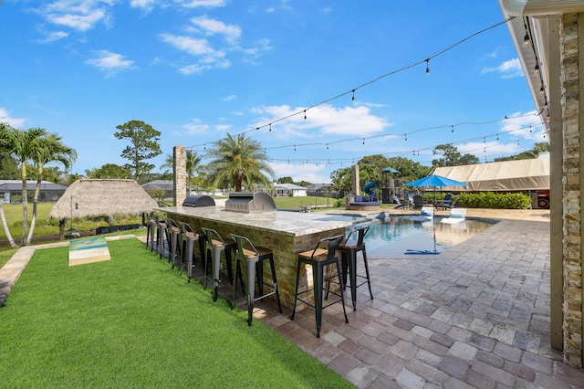 outdoor pool featuring exterior bar, an outdoor kitchen, a lawn, and a patio area
