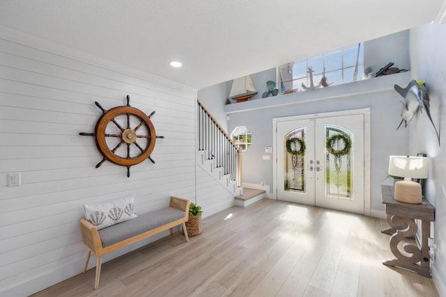 entrance foyer with french doors, stairway, wood finished floors, wooden walls, and baseboards