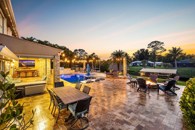 patio terrace at dusk with an outdoor fire pit, a patio area, and outdoor dining area
