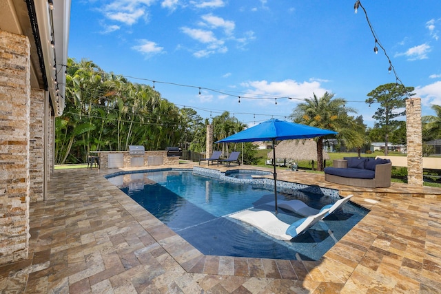 view of swimming pool with an outdoor kitchen, a patio area, and a pool with connected hot tub