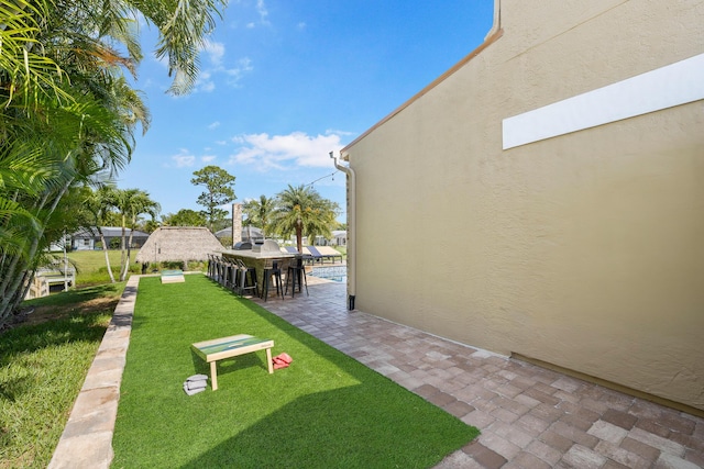 view of home's community featuring a yard, a patio, and exterior bar