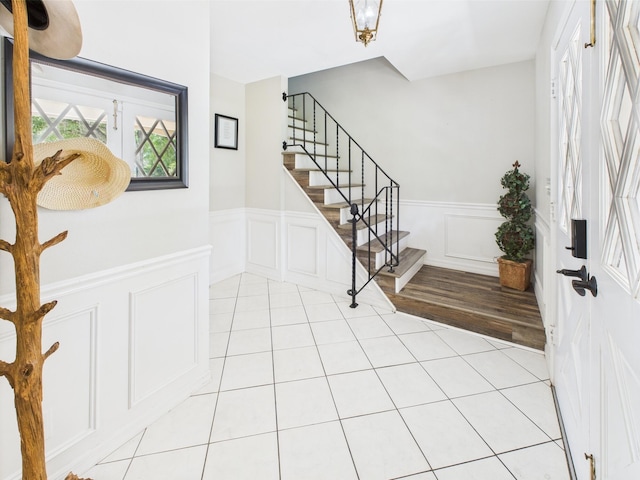 2045 SW 18th Ln, Okeechobee, FL 34974 - entrance foyer featuring stairs, a wainscoted wall, light tile patterned floors, and a decorative wall