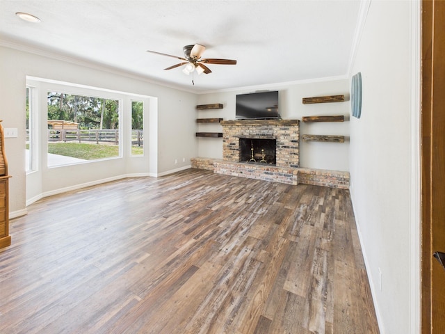 2045 SW 18th Ln, Okeechobee, FL 34974 - unfurnished living room featuring crown molding, ceiling fan, wood finished floors, a brick fireplace, and baseboards