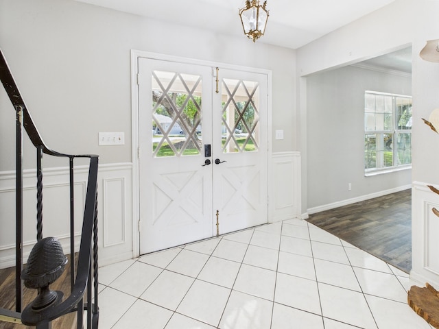 2045 SW 18th Ln, Okeechobee, FL 34974 - entrance foyer featuring a wainscoted wall, tile patterned flooring, a chandelier, a decorative wall, and ornamental molding