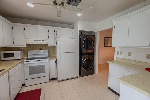 517 SE Crooked Lake Ln Unit D, Fort Pierce, FL 34982 - kitchen featuring white appliances, stacked washing machine and dryer, under cabinet range hood, light countertops, and white cabinetry