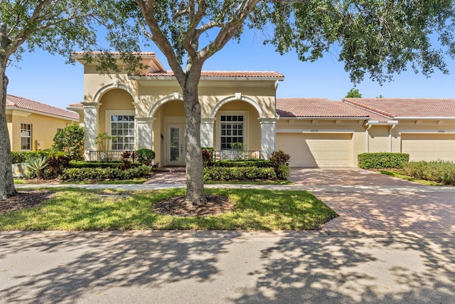 10171 SW Dolce Rd, Port Saint Lucie, FL 34986 - mediterranean / spanish house featuring a tile roof, driveway, an attached garage, and stucco siding