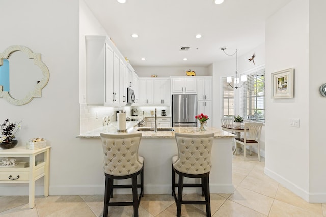 10171 SW Dolce Rd, Port Saint Lucie, FL 34986 - kitchen featuring appliances with stainless steel finishes, a sink, a peninsula, recessed lighting, and light stone countertops
