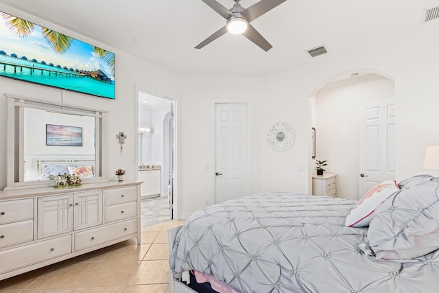 10171 SW Dolce Rd, Port Saint Lucie, FL 34986 - bedroom with arched walkways, light tile patterned floors, ensuite bath, and ceiling fan