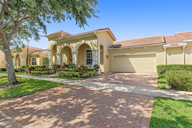 10171 SW Dolce Rd, Port Saint Lucie, FL 34986 - mediterranean / spanish house with stucco siding, an attached garage, decorative driveway, and a tiled roof