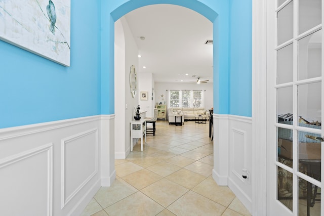 10171 SW Dolce Rd, Port Saint Lucie, FL 34986 - hallway featuring arched walkways, wainscoting, light tile patterned floors, a decorative wall, and recessed lighting