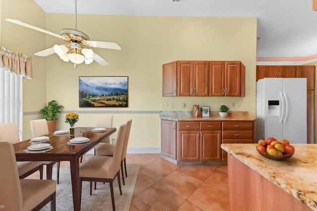 8586 Brian Blvd, Boynton Beach, FL 33472 - kitchen featuring white fridge with ice dispenser, a ceiling fan, light tile patterned flooring, brown cabinets, and light stone countertops