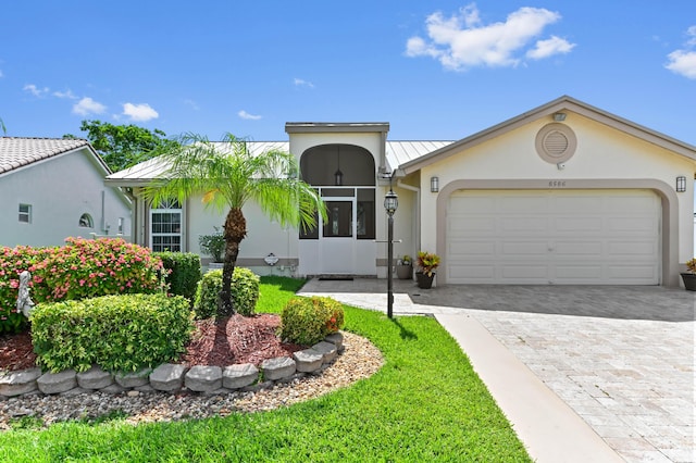 8586 Brian Blvd, Boynton Beach, FL 33472 - view of front facade with stucco siding, decorative driveway, a standing seam roof, and a garage