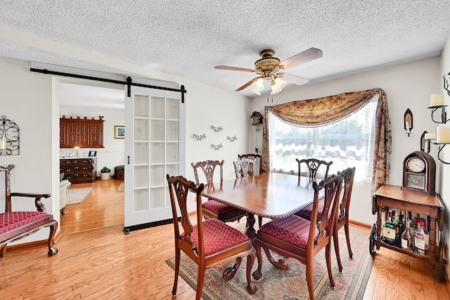 1328 SE 3rd Ave, Deerfield Beach, FL 33441 - dining room with a barn door, a ceiling fan, light wood-style flooring, and a textured ceiling