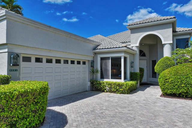 6051 NW 24th Ter, Boca Raton, FL 33496 - mediterranean / spanish-style house with a tiled roof, stucco siding, decorative driveway, and a garage