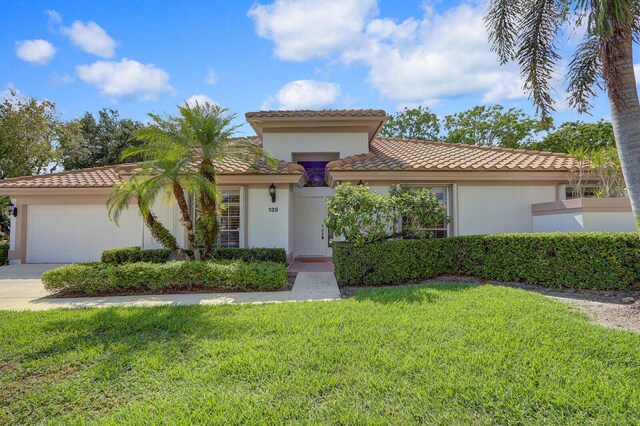 135 Eagleton Ct, Palm Beach Gardens, FL 33418 - mediterranean / spanish home featuring a tile roof, a front lawn, a garage, driveway, and stucco siding