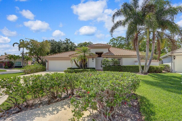 135 Eagleton Ct, Palm Beach Gardens, FL 33418 - mediterranean / spanish home featuring a tile roof, stucco siding, driveway, a garage, and a front lawn