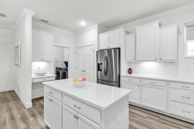 6020 Wild Olive Way, Vero Beach, FL 32966 - kitchen featuring stainless steel fridge, washer and dryer, crown molding, white cabinetry, and light wood-style flooring