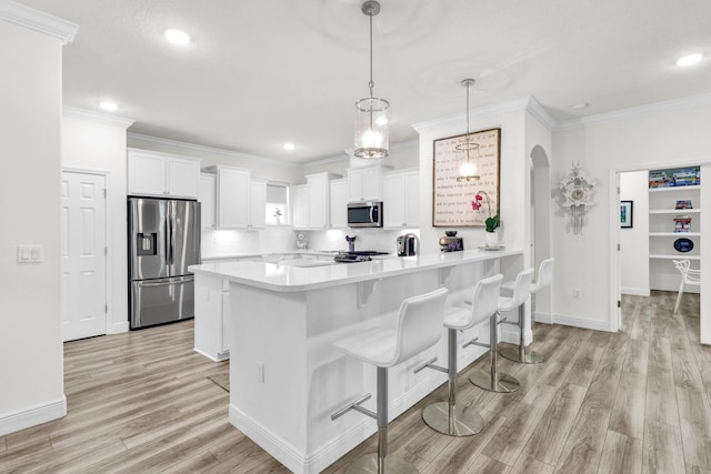 6020 Wild Olive Way, Vero Beach, FL 32966 - kitchen with stainless steel appliances, arched walkways, light countertops, crown molding, and light wood-style flooring