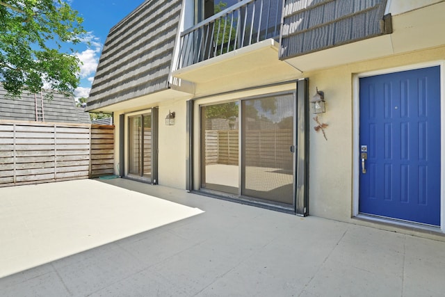 707 7th Ter, Palm Beach Gardens, FL 33418 - doorway to property with stucco siding, a patio area, mansard roof, and a balcony