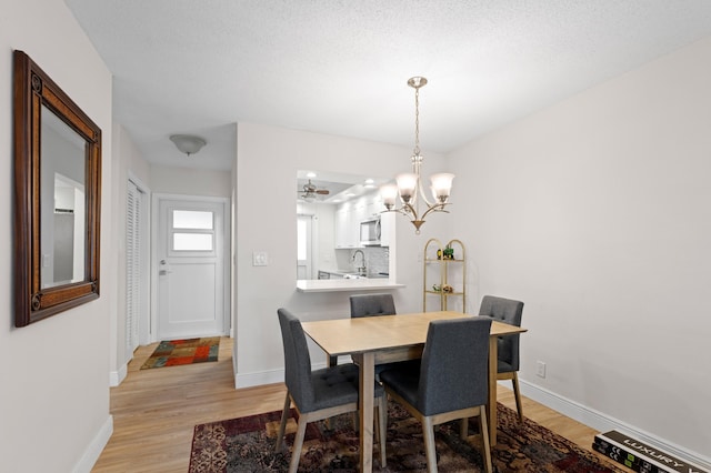 2050 NE 39th St Unit 110S, Lighthouse Point, FL 33064 - dining space featuring light wood-style floors, a chandelier, and baseboards
