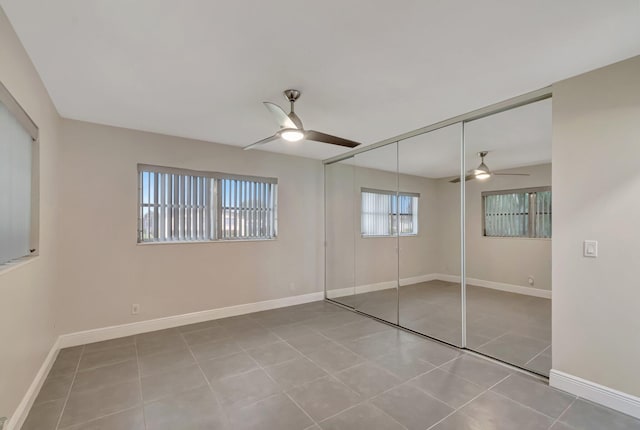 unfurnished bedroom featuring tile patterned floors, a closet, ceiling fan, and baseboards
