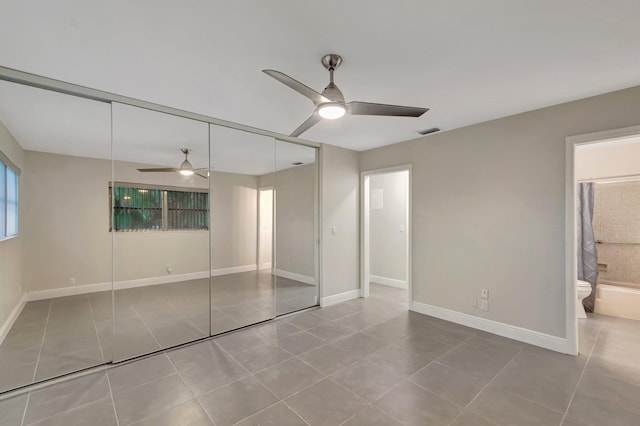 unfurnished bedroom featuring tile patterned floors, a closet, ensuite bathroom, and baseboards