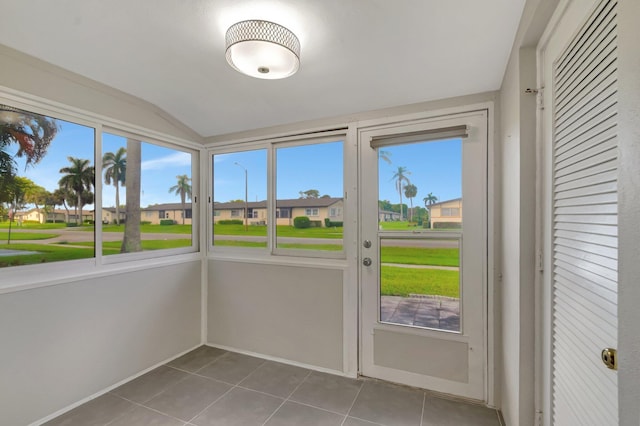unfurnished sunroom with plenty of natural light, lofted ceiling, and a residential view