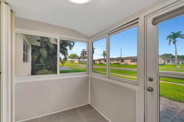 unfurnished sunroom with lofted ceiling, tile patterned flooring, and a residential view